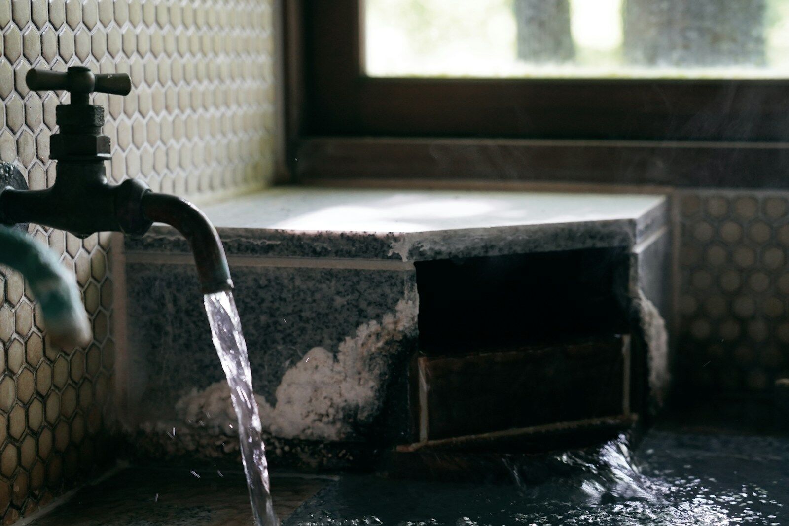 Aus einem Wasserhahn läuft Wasser über eine Arbeitsfläche.